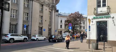 a woman is walking down a city street with cars at Cozy Apartment 4A in Kraków