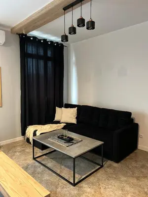 a living room with a black couch and a table at La Ville - Rouge in Zator