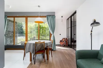 a dining room and living room with a table and chairs at Jesionowa Homely Apartment with Garden by BookingHost in Kraków