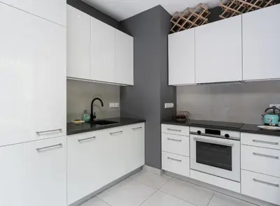 a white kitchen with white cabinets and a sink at Jesionowa Homely Apartment with Garden by BookingHost in Kraków