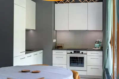 a small kitchen with white cabinets and a table at Jesionowa Homely Apartment with Garden by BookingHost in Kraków