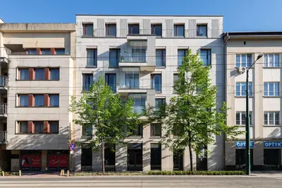 a tall white building with trees in front of it at Kościuszki apartment with parking by Nearto pl in Kraków