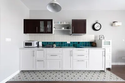 a kitchen with white cabinets and a clock on the wall at Kościuszki apartment with parking by Nearto pl in Kraków