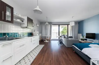a bedroom with a king sized bed and a kitchen at Kościuszki apartment with parking by Nearto pl in Kraków