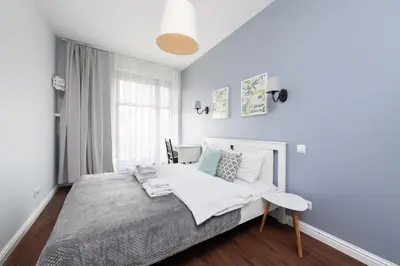a white bedroom with a bed and a desk at Kościuszki apartment with parking by Nearto pl in Kraków