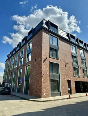 a large brick building with windows on a street at Jungle Apartment in Kraków