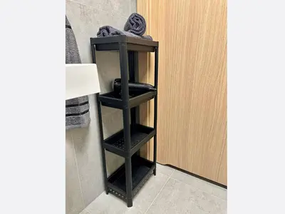 a black shelf in a bathroom next to a door at Jungle Apartment in Kraków