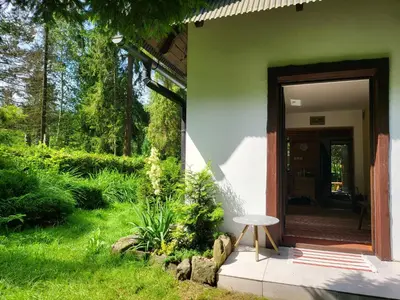a green house with a stool next to a door at Dom Pod Salamandrą Koninki in Poręba Wielka