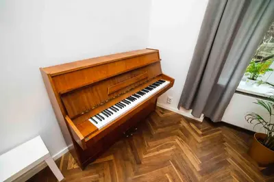 a wooden piano in a room with a window at Classic Loft Arena in Kraków