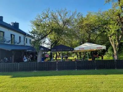a patio with umbrellas in a park next to a house at Noclegi Primavera in Jaśkowice