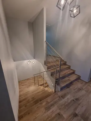 a staircase with a metal railing and wooden floors at Noclegi Primavera in Jaśkowice