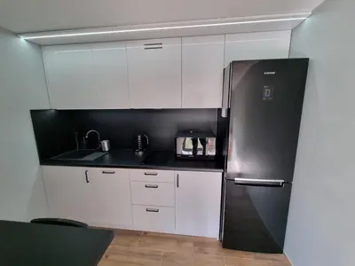 a kitchen with white cabinets and a stainless steel refrigerator at Noclegi Primavera in Jaśkowice
