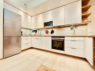 a kitchen with white cabinets and a refrigerator at Four Apartaments Daszyńskiego in Kraków