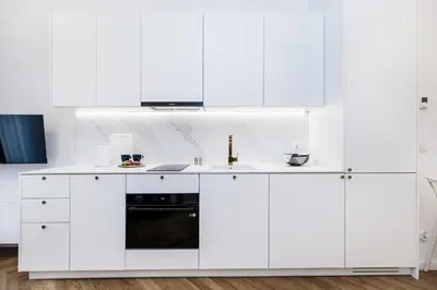 a white kitchen with white cabinets and a sink at BoB Elite - Bonerowska in Kraków