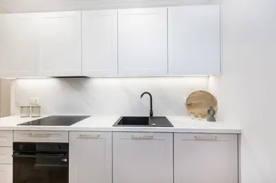 a white kitchen with white cabinets and a sink at BoB Elite - Bonerowska in Kraków