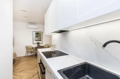 a kitchen with white cabinets and a sink at BoB Elite - Bonerowska in Kraków
