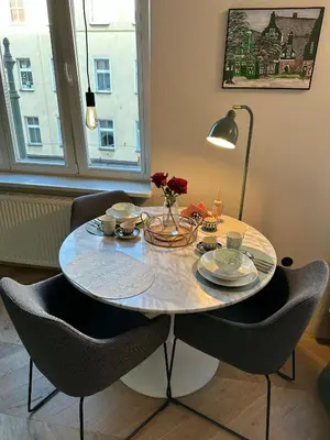a dining room table with chairs and a table with flowers on it at Heron Apartment - Old Town Kraków in Kraków