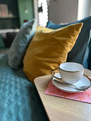 a coffee cup and saucer on a table with pillows at Heron Apartment - Old Town Kraków in Kraków