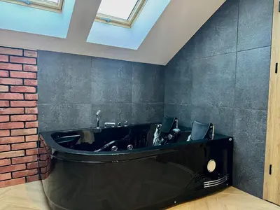 a black bathroom with a black tub and a brick wall at Willa Tulipanowa in Przeciszów