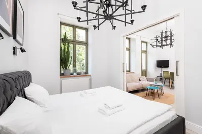 a white bedroom with a bed and a chandelier at Modern Nest - in the Heart of Kraków - Old Town - by Upstairs in Kraków