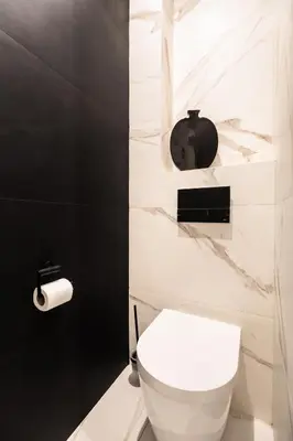 a bathroom with a white toilet and a black wall at Modern Nest - in the Heart of Kraków - Old Town - by Upstairs in Kraków