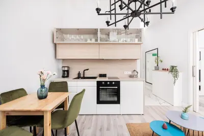 a kitchen with white cabinets and a wooden table at Modern Nest - in the Heart of Kraków - Old Town - by Upstairs in Kraków