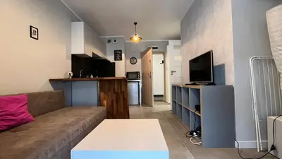 a living room with a couch and a kitchen at Small Studio in Kraków
