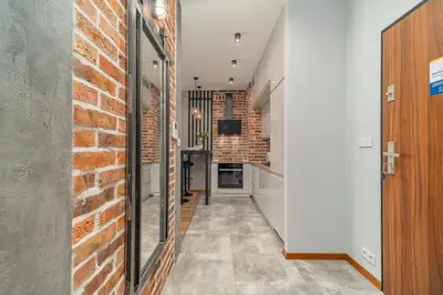 a hallway with a red brick wall and a kitchen at Grzegórzki Apt - Top location and Parking by Rentujemy in Kraków