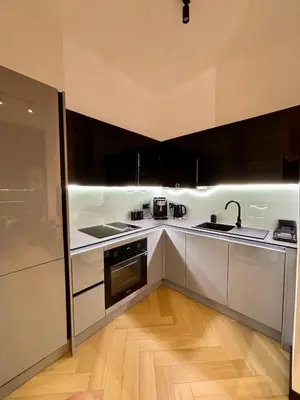 a kitchen with white cabinets and black appliances at Old Town Libra Apartment in Kraków