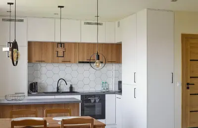 a kitchen with white cabinets and a table and chairs at Słowackiego Avenue Cozy Stay Studio by BookingHost in Kraków