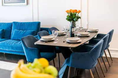 a dining table with chairs and a blue couch at Prestige Central Apartment with Sauna & Parking in Kraków