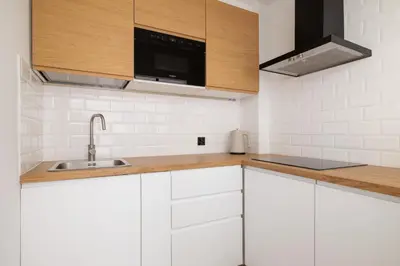 a kitchen with white cabinets and a sink at Apartment with Balcony - Łobzowska 57 street in Kraków