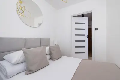 a bedroom with a white bed with pillows and a mirror at Apartment with Balcony - Łobzowska 57 street in Kraków