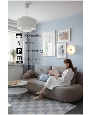 a woman sitting on a couch reading a book at OSKA Apartment near Expo, Tauron Arena in Kraków