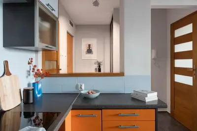 a kitchen with orange cabinets and a black counter top at OSKA Apartment near Expo, Tauron Arena in Kraków