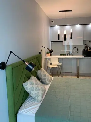 a bedroom with a bed with a green headboard and a kitchen at Rajska 3 in Kraków