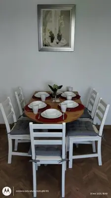 a dining room table with white chairs and a table with plates at Apartament na Kazimierzu in Kraków