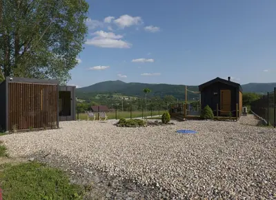 a house with a gravel yard and a fence at Magiczny Widok Tiny House in Jurków