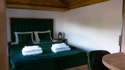 a bedroom with a green bed with towels on it at Magiczny Widok Tiny House in Jurków