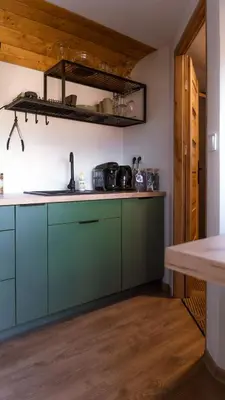 a kitchen with green cabinets and a wooden floor at Magiczny Widok Tiny House in Jurków