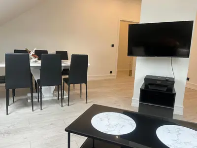a dining room with a table with chairs and a flat screen tv at Villa Kraków 2 in Kraków