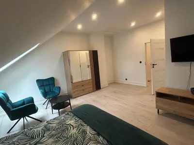a bedroom with a bed and two chairs and a television at Villa Kraków 2 in Kraków