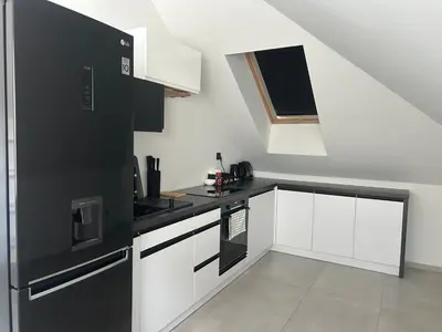 a kitchen with white cabinets and black appliances at Villa Kraków 2 in Kraków
