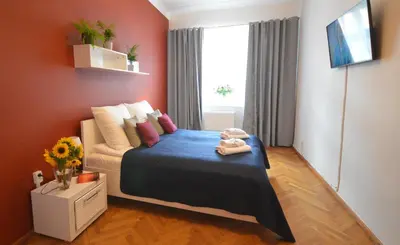 a bedroom with a bed with blue sheets and a window at KING JAGIELLO Apartment in Kraków