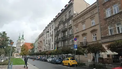 a city street with buildings and a yellow car at KING JAGIELLO Apartment in Kraków