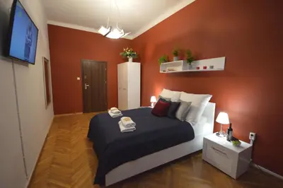 a bedroom with a large bed with orange walls at KING JAGIELLO Apartment in Kraków