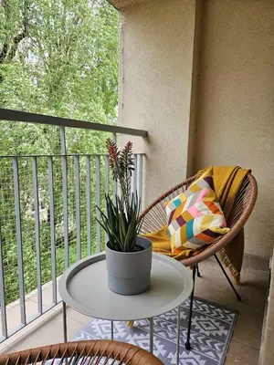 a table and a chair on a balcony with a plant at Lovely Sparkly Apartment in Kraków