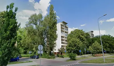 a building on a street with trees and a street sign at Lovely Sparkly Apartment in Kraków