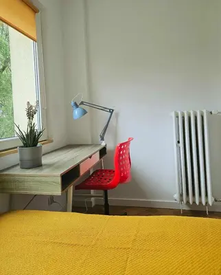 a desk with a red chair next to a window at Lovely Sparkly Apartment in Kraków