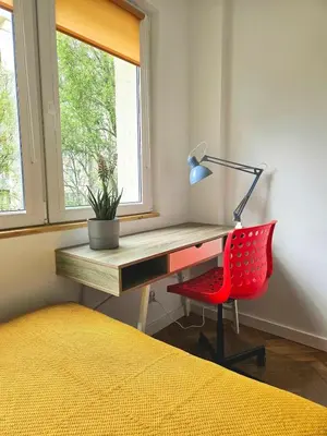 a desk with a red chair next to a window at Lovely Sparkly Apartment in Kraków